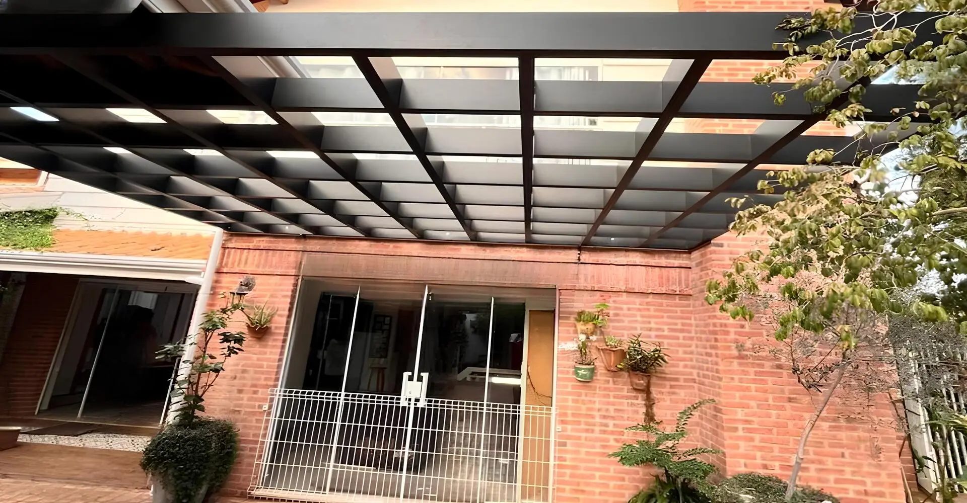 Pergolado de alumínio cruzado instalado em jardim residencial com sombreamento parcial em Mogi Mirim SP — Toldos em Mogi Mirim